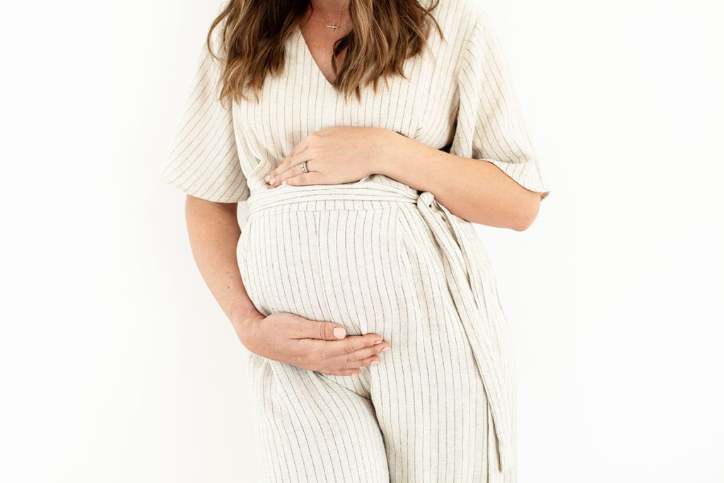 Modern maternity image of a mother in fourth trimester wearing a striped jumpsuit