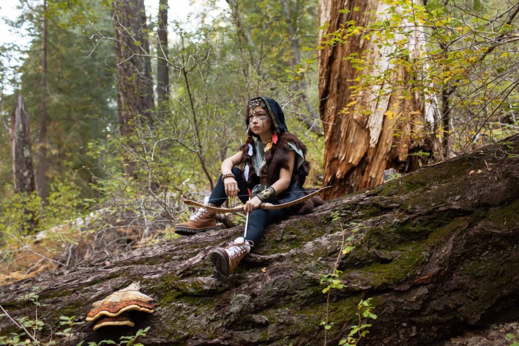Halloween costume viking mountain explorer photoshoot, girl sitting on tree log