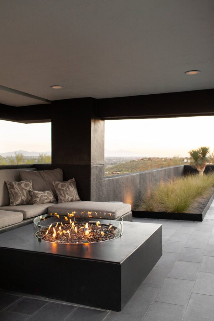Built-in fire pit glowing at dusk at a Tucson mid-century home, photographed by Fletcher and Co for Box Hill Landscape Design.