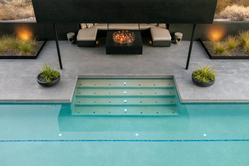 Built-in fire pit glowing at dusk at a Tucson mid-century home, photographed by Fletcher and Co for Box Hill Landscape Design.