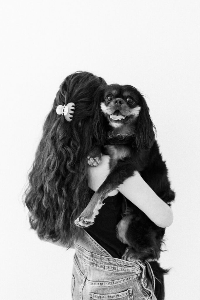 Child holding her dog who is smiling back at the camera during a modern portrait photography session in Tucson, Arizona.