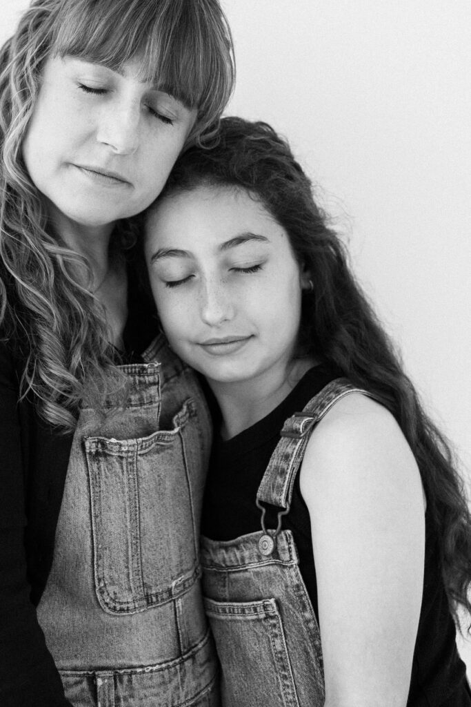 Mother tenderly snuggling her daughter with their eyes closed during a modern motherhood studio photography session in Tucson, Arizona.