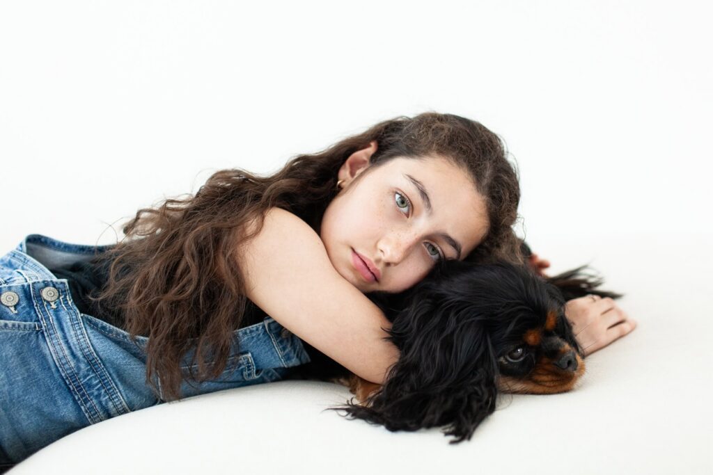 A child snuggling her dog while laying down together during a modern portrait photography session in Tucson, Arizona.