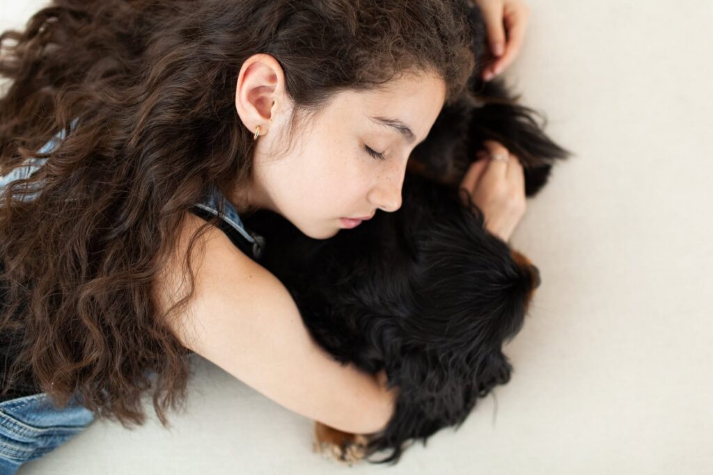 A child with her eyes closed snuggling her dog while laying down together during a modern portrait photography session in Tucson, Arizona.