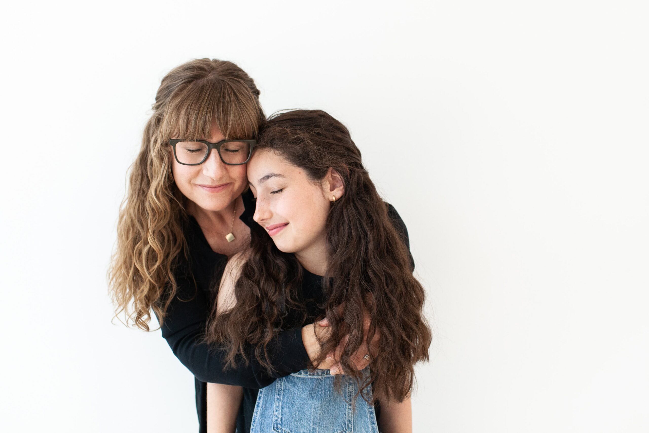 Mother holding her daughter with their eyes closed during a candid studio motherhood photography session in Tucson, Arizona.