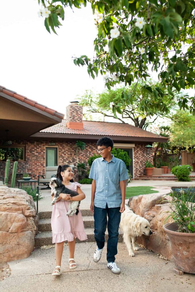 Tucson family photography session captured in their backyard pool area with the siblings walking their dogs