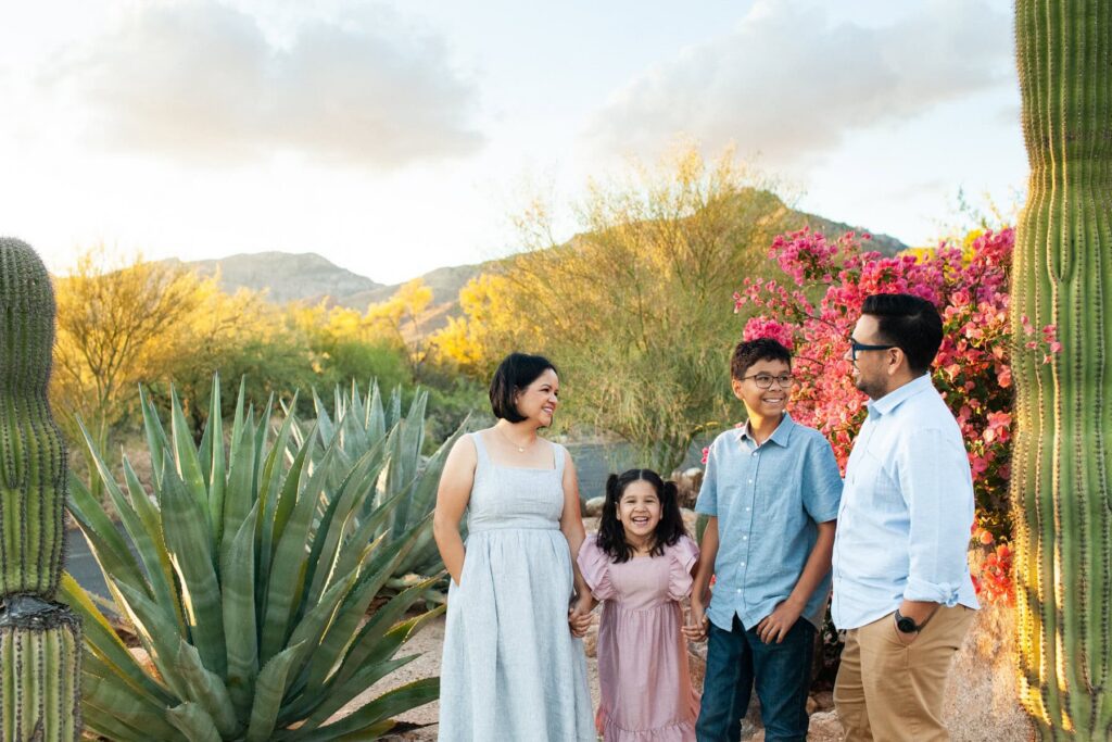 Tucson family photography session captured in their front desert property yard where the parents and children are standing and  laughing together